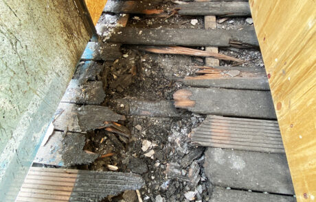 Burnt balcony decking from a fire started by a carelessly discarded cigarette from two floors up